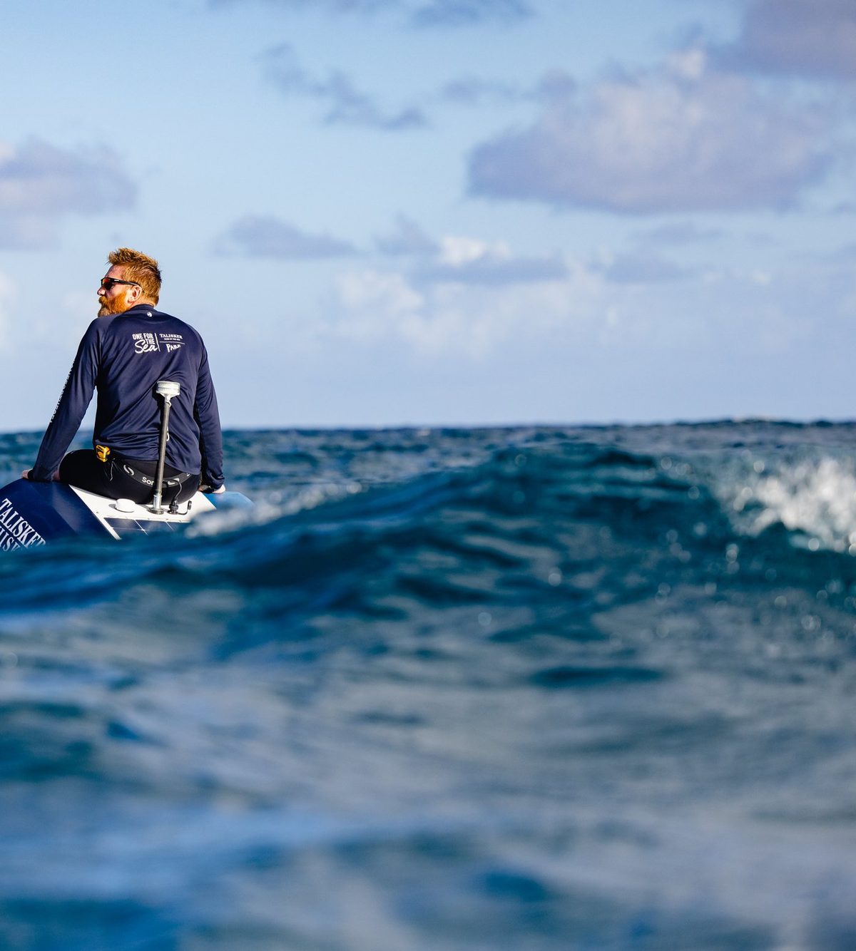 Rob Murray sitting on the stern of his ocean rowing boat, looking out over Atlantic swell